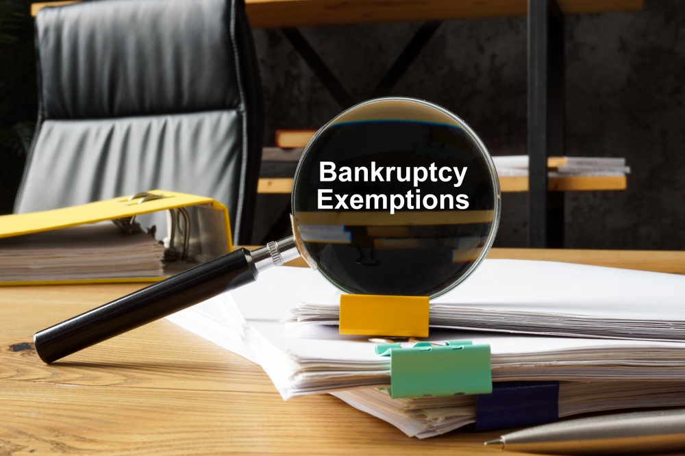 Bankruptcy exemptions concept. A magnifying glass lies on a stack of papers.