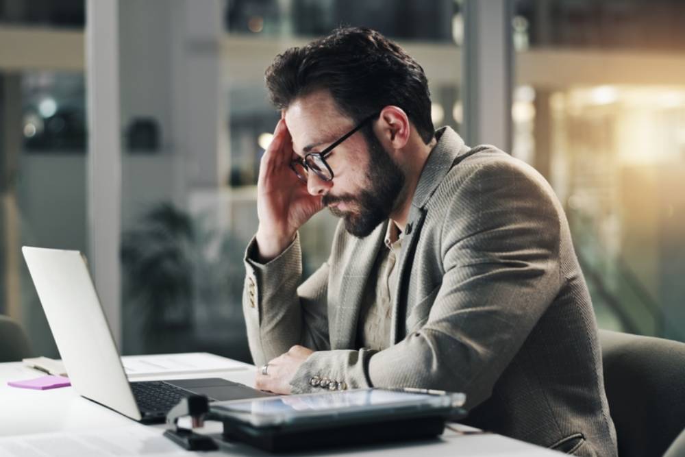 Businessman, laptop and night with headache or stress in office for finance, debt or mistake