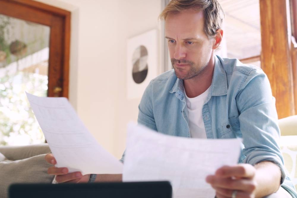 Man, thinking and relax with documents at house for tablet, financial bankruptcy or payment debt of mortgage. Person